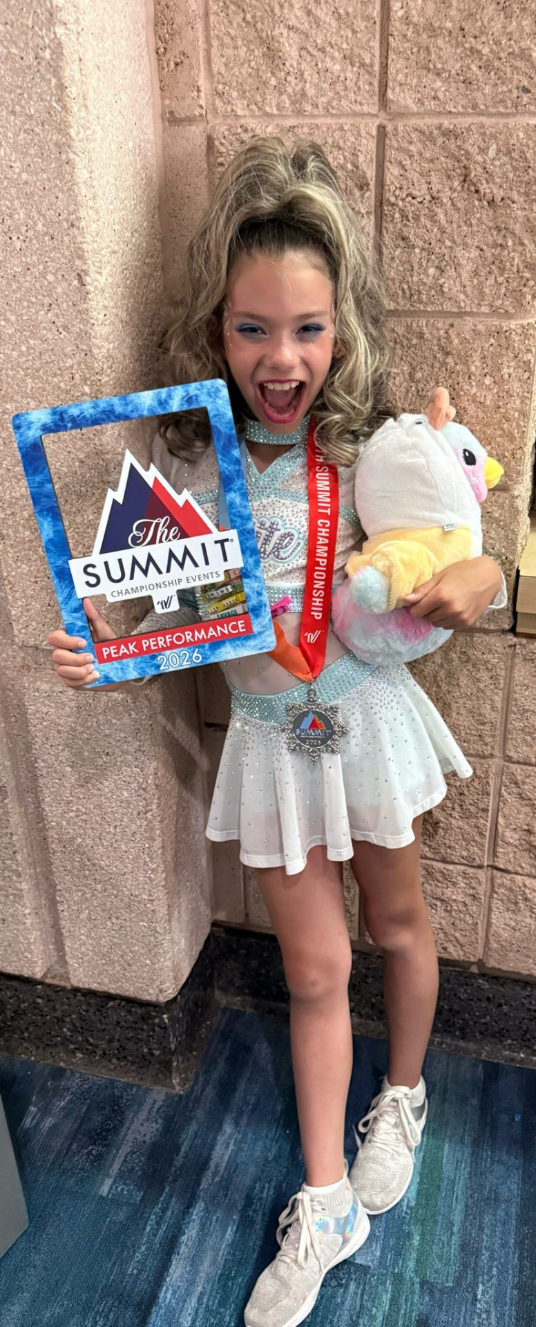 An Elite Athletics athlete holding a Summit Peak Performance 2026 award and a plush toy