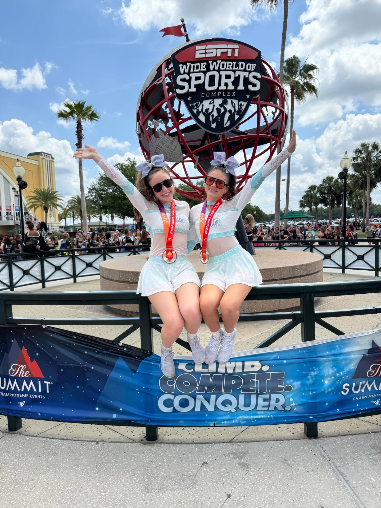 Two Elite Athletics athletes celebrating with Summit medals and raised arms