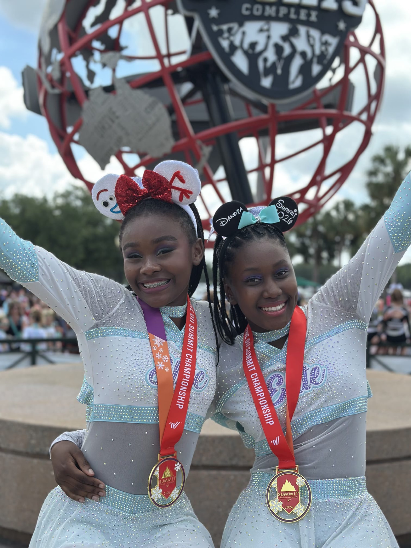 Two smiling Elite Athletics teammates showing their Summit medals