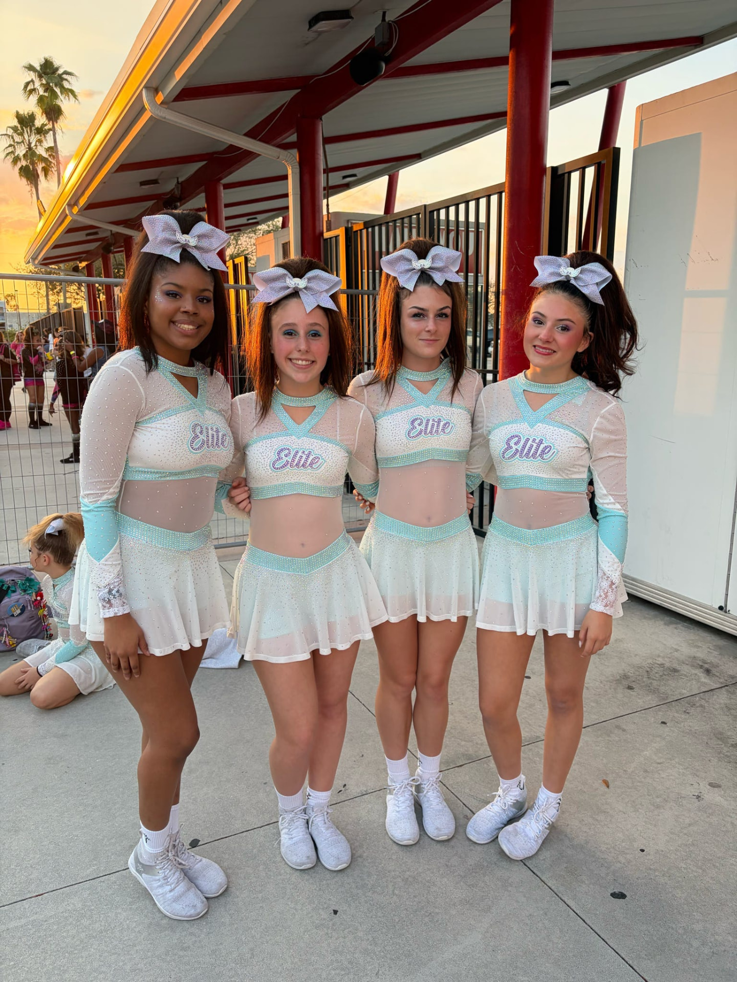 Four Elite Athletics teammates posing in teal and white competition uniforms